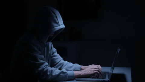 An individual in a dark room coding